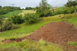 In a slight setback, the digger hasn't found any rotten rock on the site, which is required for the base layer under the track and foundations. After hunting around for it on site, the digger goes in search for some over on the croft (the alternative would be buying it in).