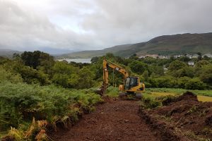 Luckily, some rotten rock is found just over the burn on the croft, so the digger driver makes himself a temporary road up to the source of the rock, before digging it up and transporting it across.