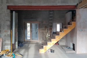 As seen from the main room: instead of a handrail or solid wall on this side of the stairs, there will be vertical battens through which you'll see the stairs and the wall behind. The understairs space will be enclosed with a hidden access door. The area the other side of the stairs will be the upstairs toilet.