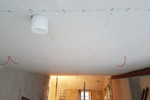 Here you can see where the joiners have cut holes in the plasterboard to bring through cables for the lights and smoke alarm and, in the foreground, the end of the white MVHR plenum, which will be cut down so that it's flush with the ceiling.